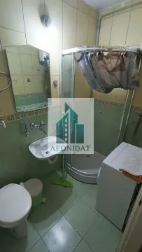 Small bathroom with a shower cabin, washbasin, toilet, and washing machine. - image 9