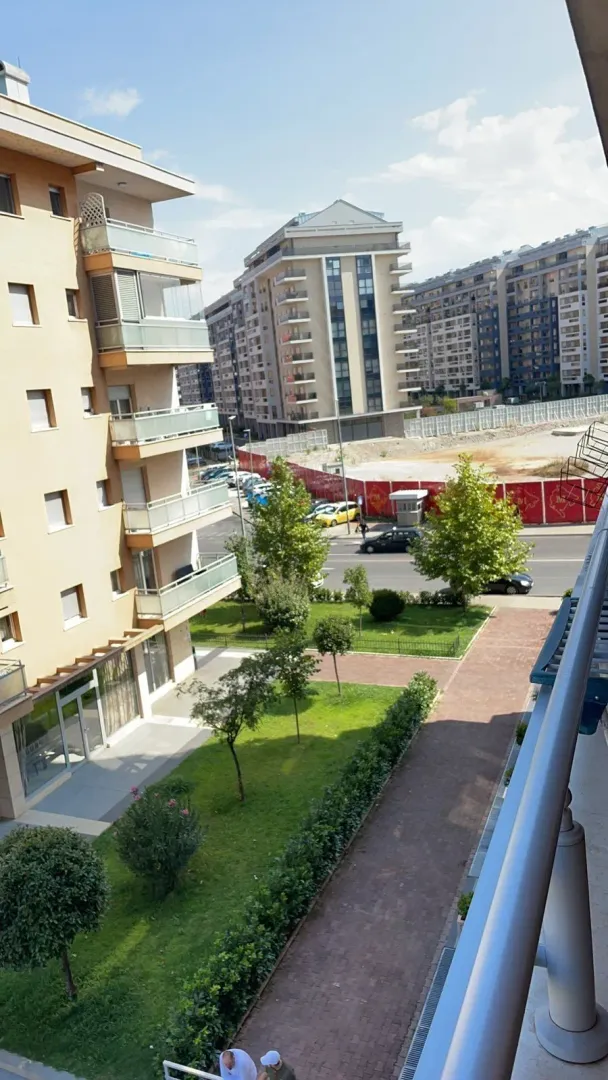 Pogled sa balkona na uređeno dvorište i stambene zgrade.