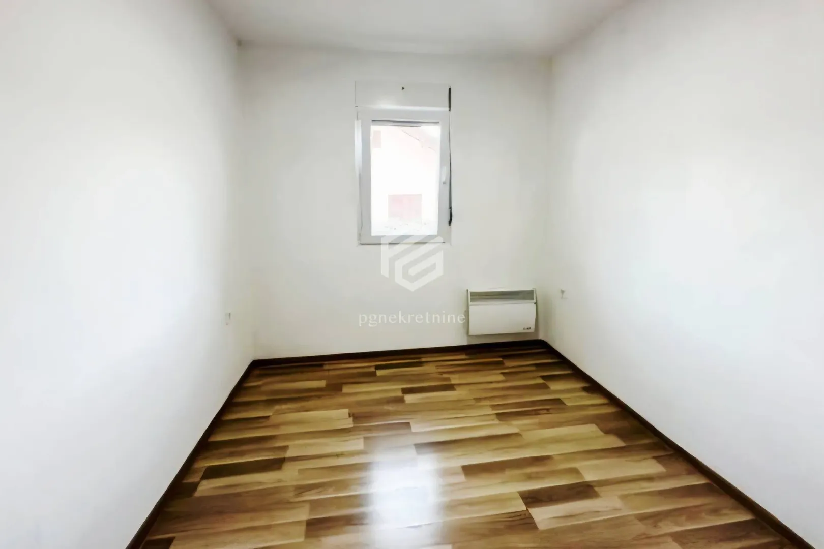Empty room with laminate flooring and white walls.
