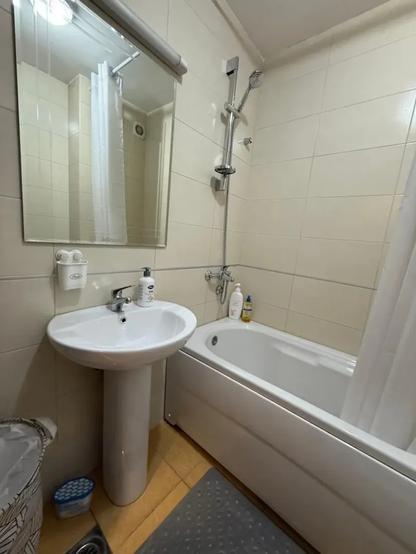 Smaller bathroom with a bathtub, washbasin, and mirror.