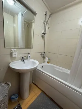 Smaller bathroom with a bathtub, washbasin, and mirror. - image 8