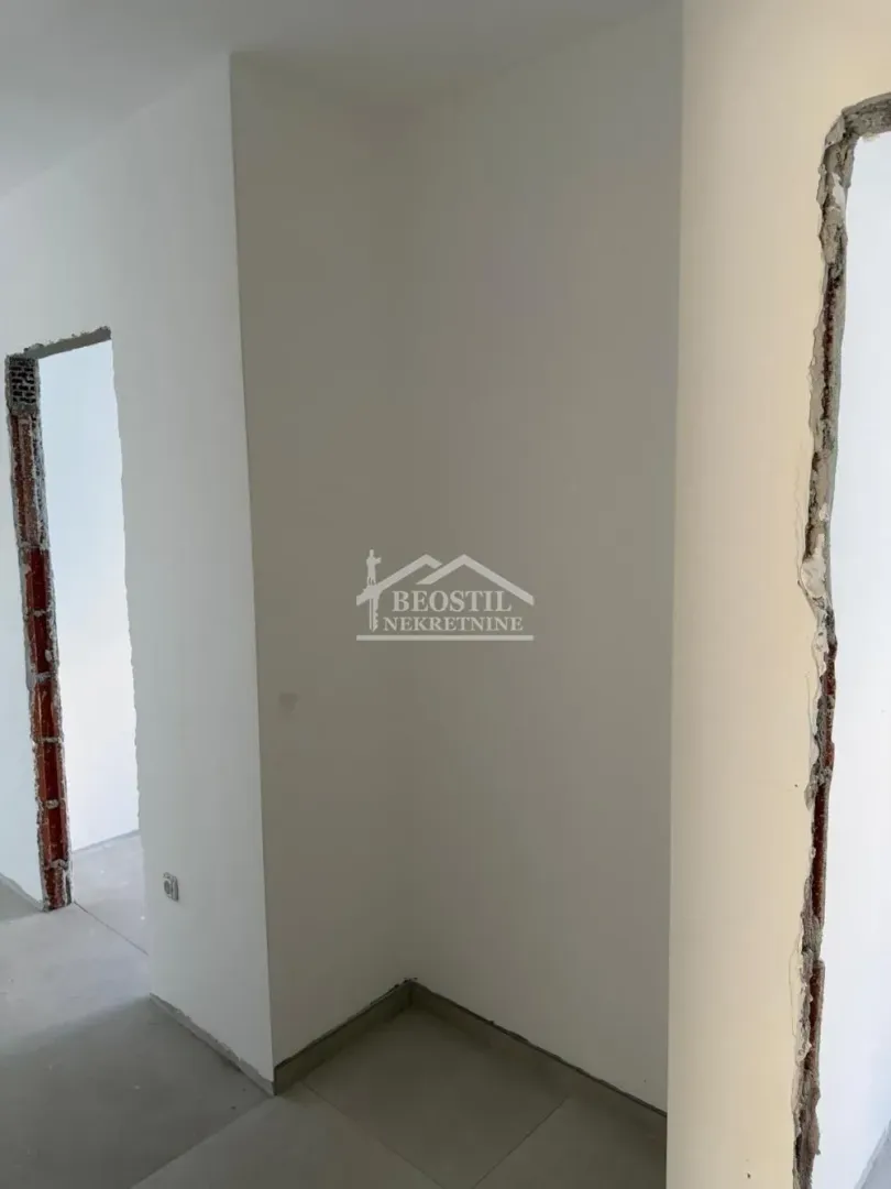 Prikaz dela enterijera sa belim zidovima i otvorima za vrata u fazi renoviranja.