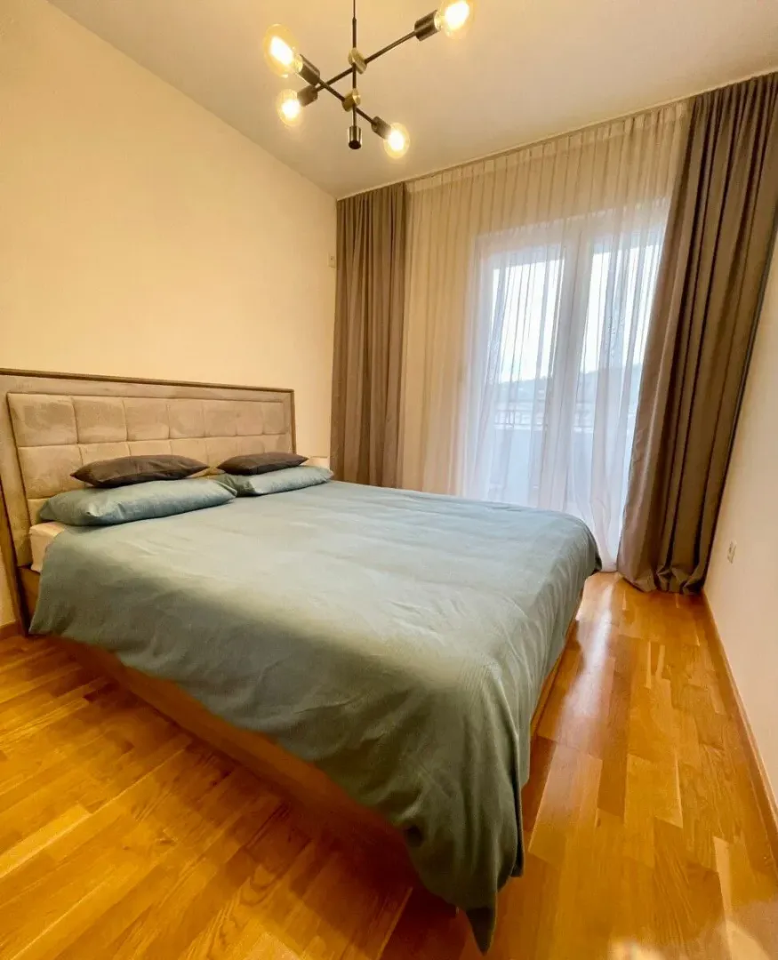 Furnished bedroom with a double bed, wooden flooring, and access to the terrace.