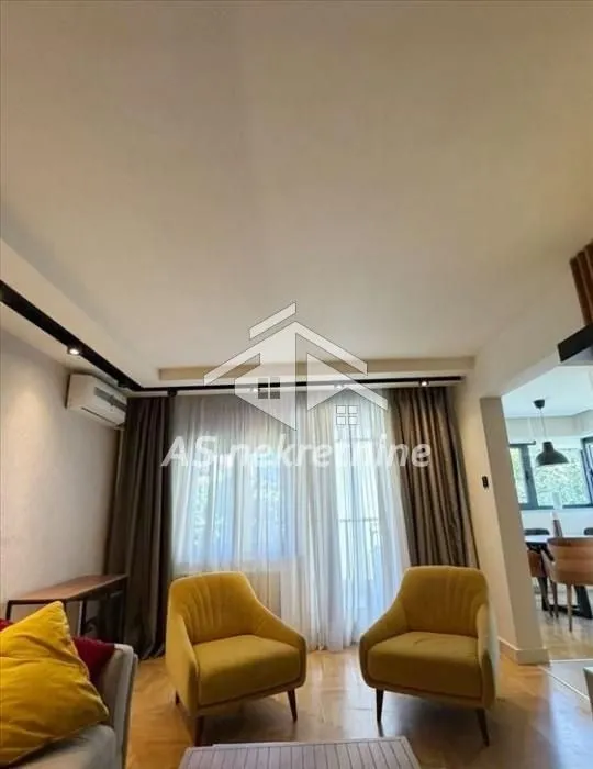 Living room with armchairs and a view of windows with curtains.