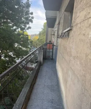 Dugačak popločani balkon sa metalnom ogradom i pogledom na zelenilo. - image 2
