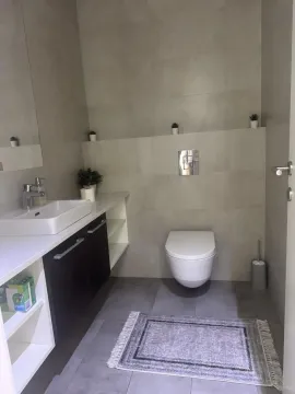 Modern bathroom equipped with a washbasin, wall-hung toilet, and gray tiles. - image 5