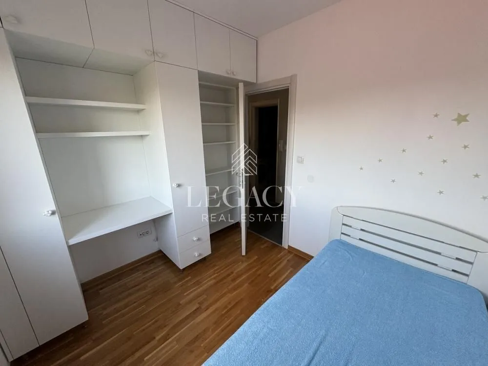 Nameštena spavaća soba sa krevetom, ugradnim plakarom i radnim stolom.