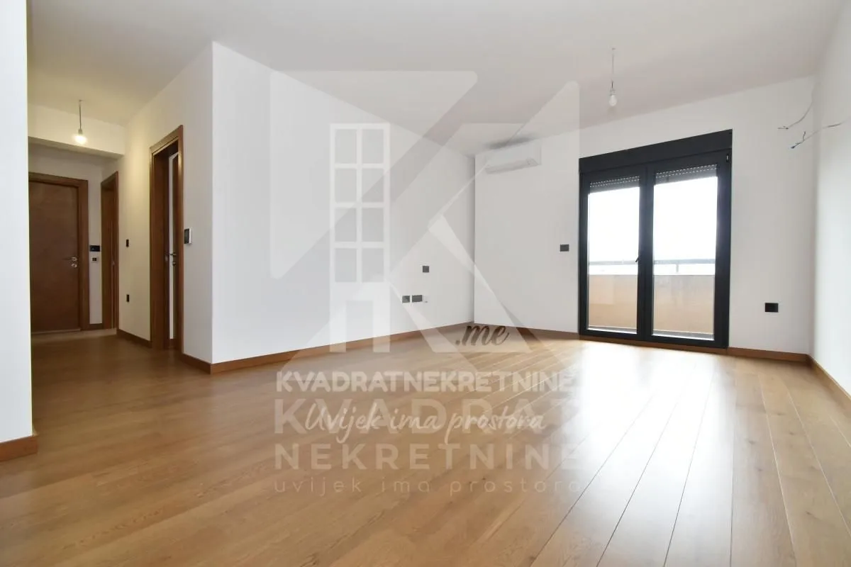 Empty living room with wooden flooring and access to the terrace.