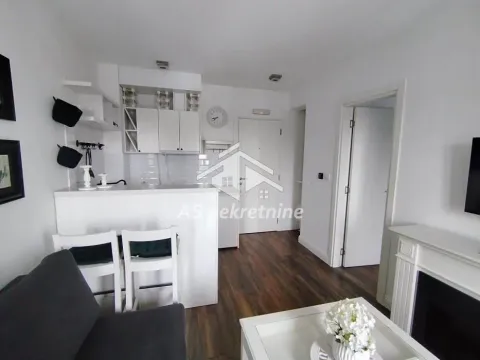 Small white kitchen with a breakfast bar and dining chairs integrated into the living area. - image 8