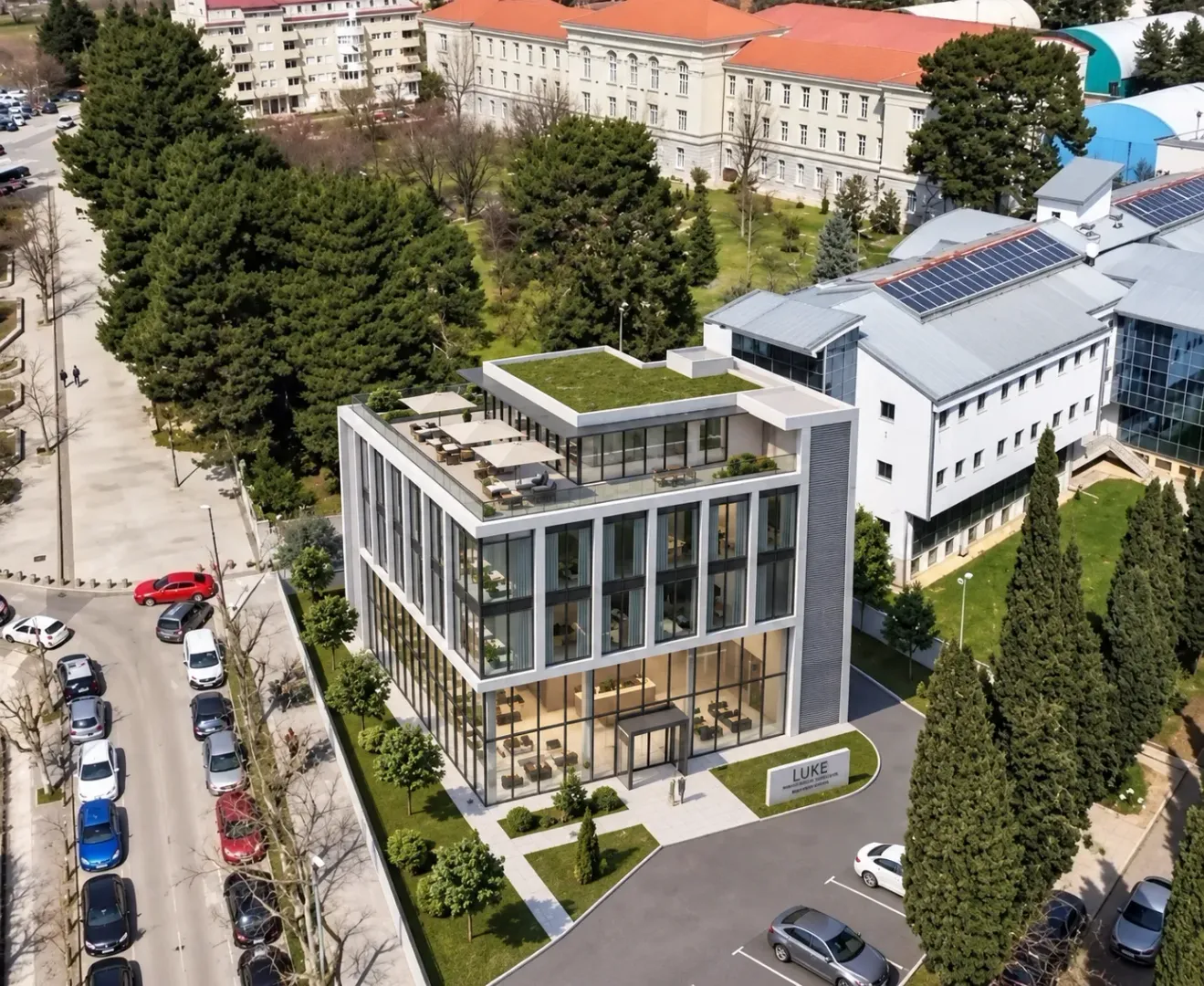 Pogled iz vazduha na modernu poslovnu zgradu sa uređenom okolinom.