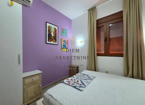 Small bedroom with a bed, purple accent wall, and a window with curtains. - image 9