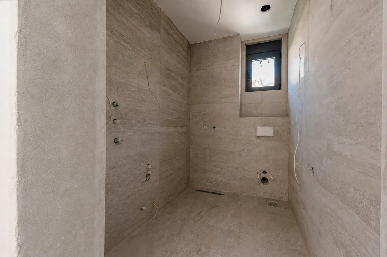 Bathroom under renovation tiled with ceramic tiles and prepared installations.