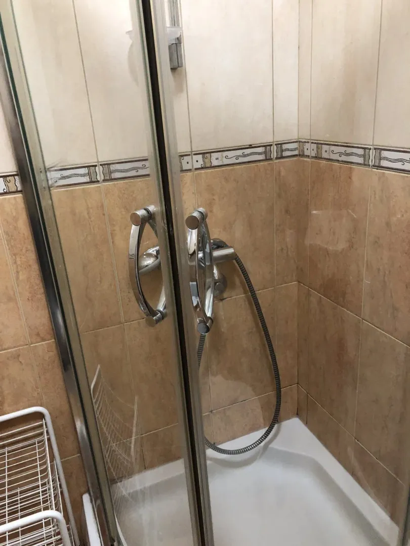 Shower cabin with glass doors and ceramic tiles in a bathroom.