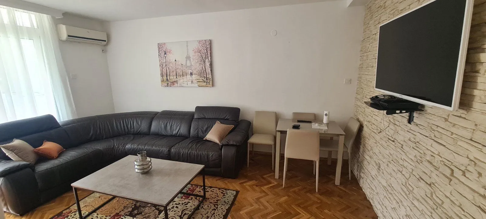 Dnevna soba sa kožnom ugaonom garniturom i trpezarijskim stolom.