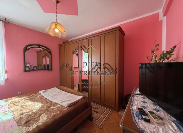 Furnished bedroom with pink walls and a wooden wardrobe.