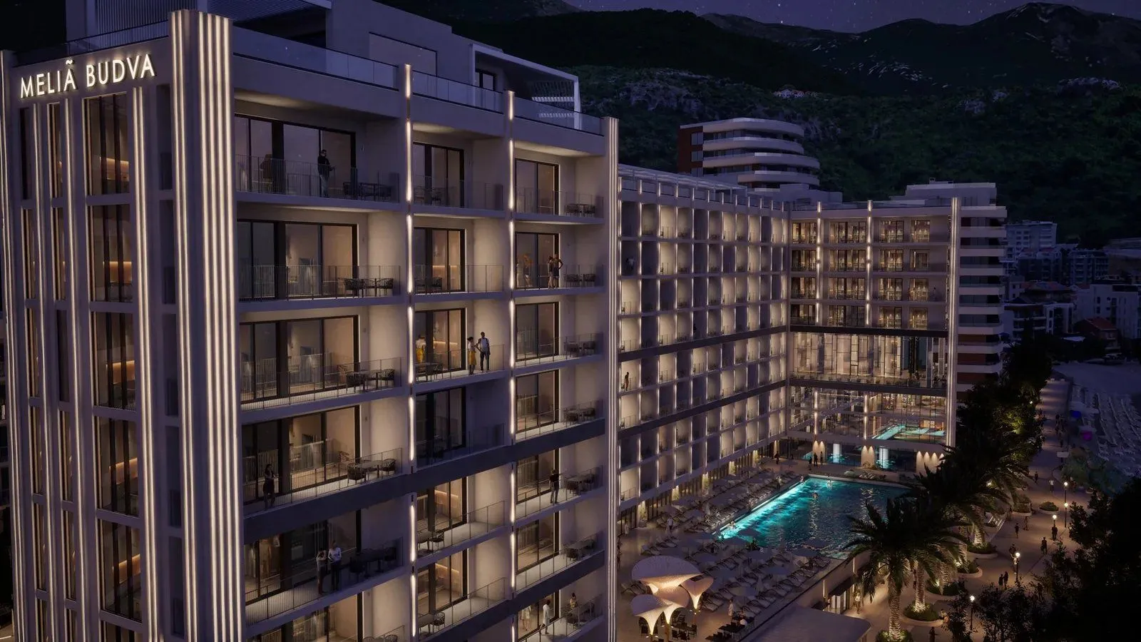 Noćni prikaz moderne hotelske zgrade sa osvijetljenim balkonima i bazenom.
