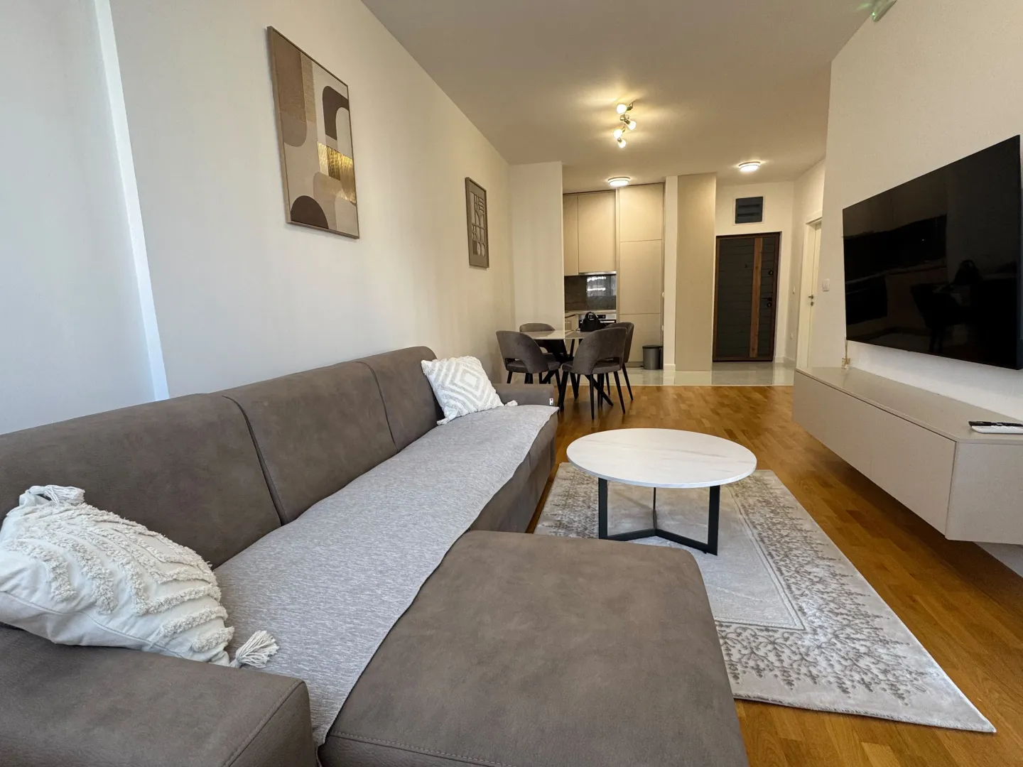 Living room with a sofa, coffee table, and TV, connected to the dining area and kitchen.