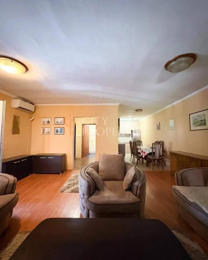 Furnished living room with a seating set and a dining area in the background.