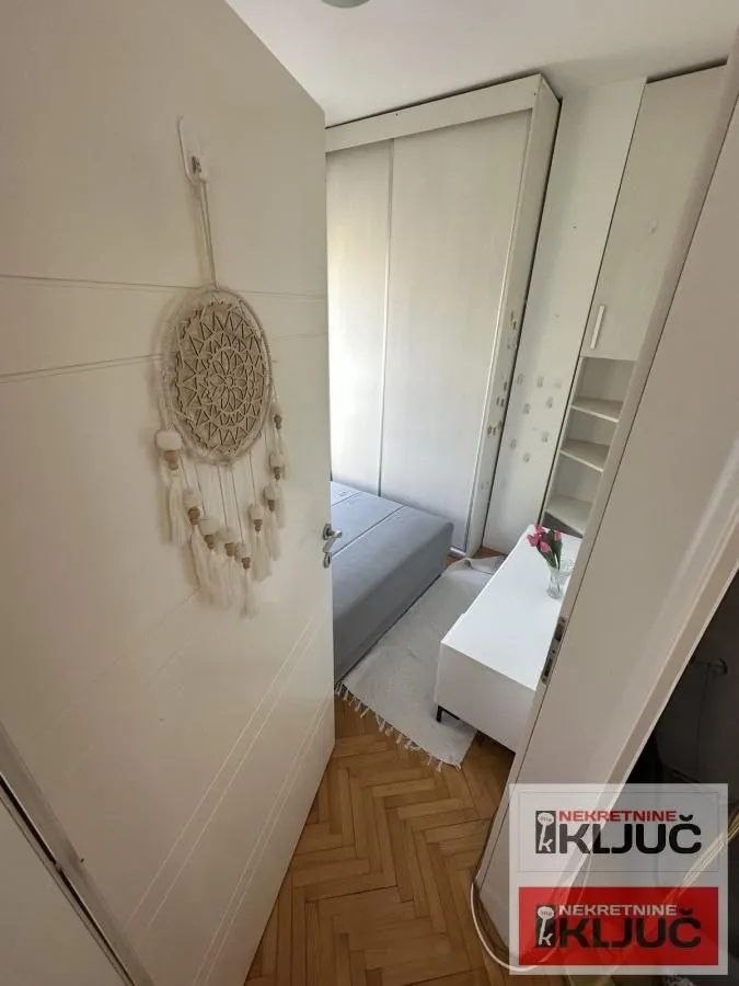Pogled iz hodnika u nameštenu spavaću sobu sa ormanom i krevetom.