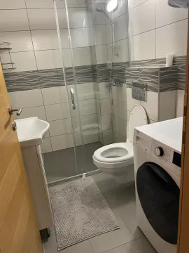 Kompaktno opremljeno kupatilo sa tuš kabinom, WC šoljom, umivaonikom i mašinom za veš. - image 2