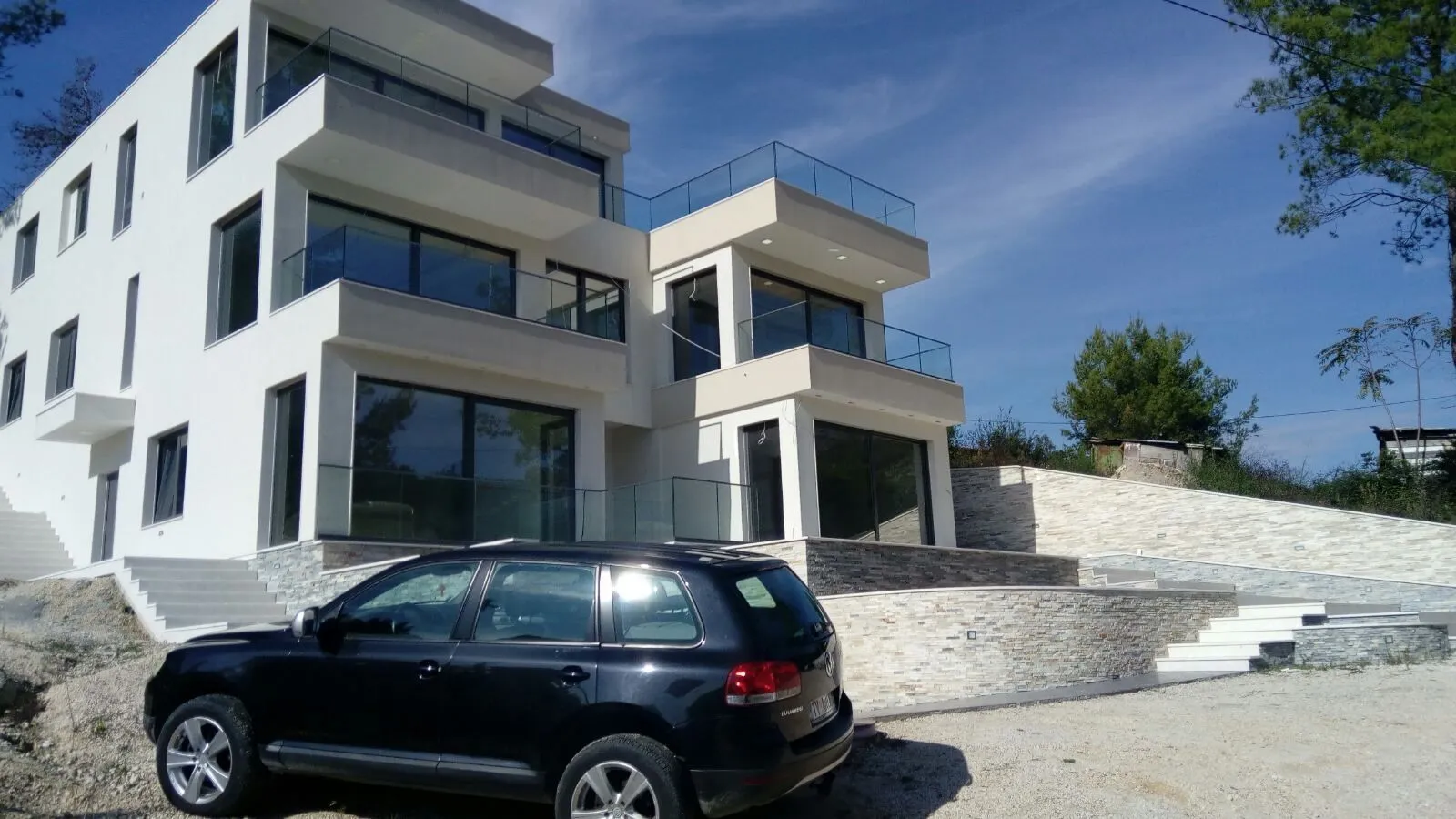 Eksterijer moderne višespratne zgrade sa staklenim terasama.