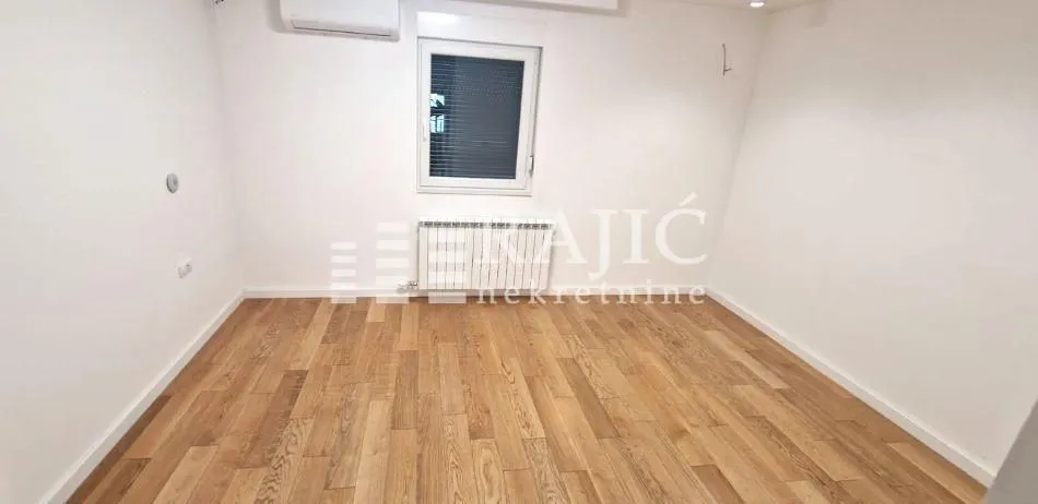 Empty room with laminate flooring and white walls.