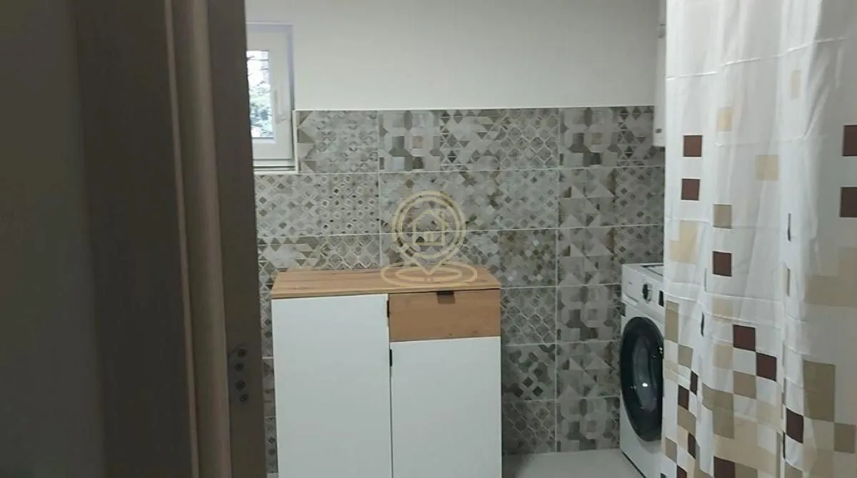 Bathroom with tiled walls, a vanity unit, and a washing machine.