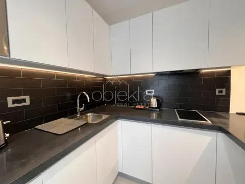 Modern kitchen with white cabinets, black countertop, and dark tiles. - image 10