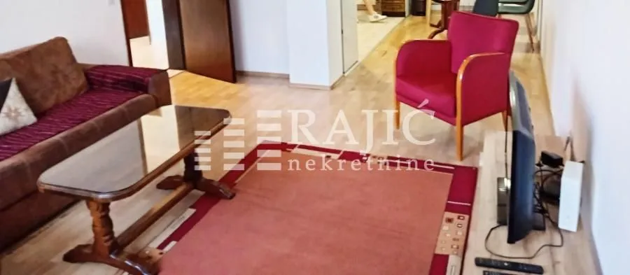 Living room with sofa, armchair, and television.