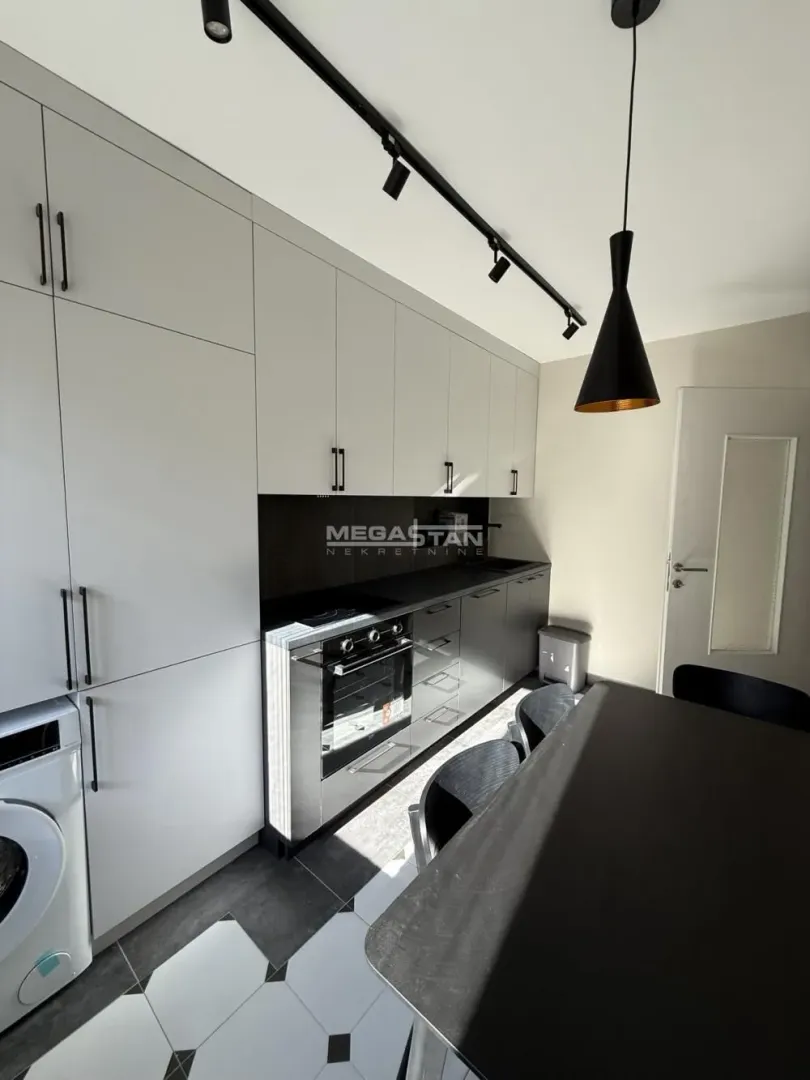 Modern kitchen with white and dark cabinets and a built-in oven.