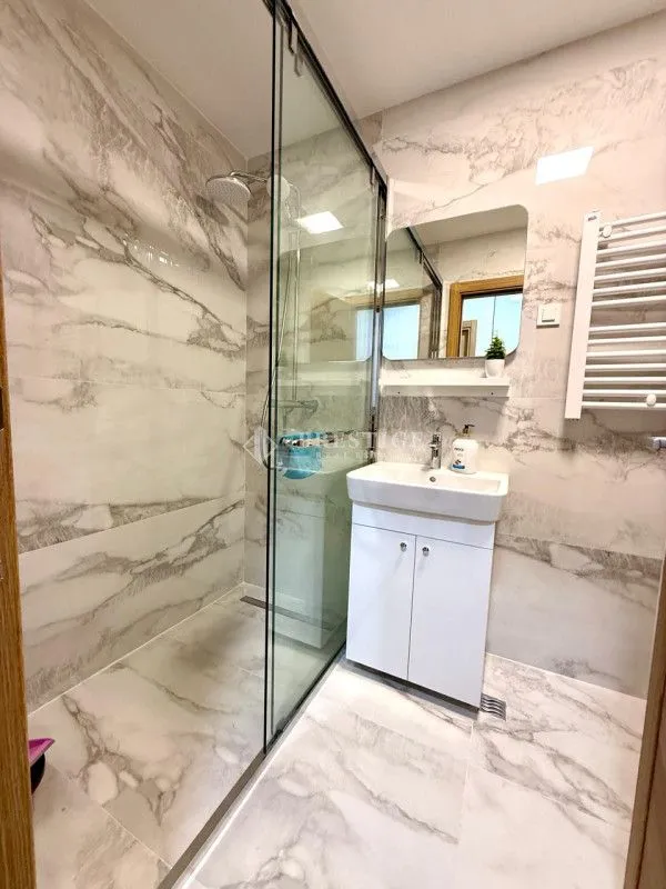 Modern bathroom with a glass shower enclosure and white vanity.
