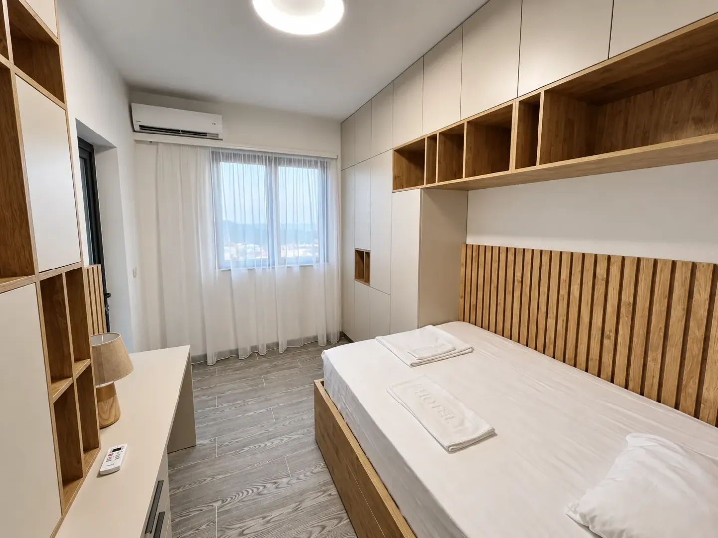 Furnished bedroom with built-in wardrobes and a wooden bed headboard.
