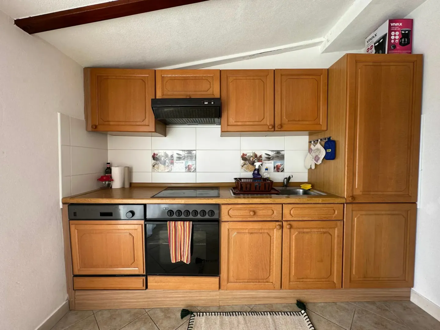 Small wooden kitchen with built-in home appliances.