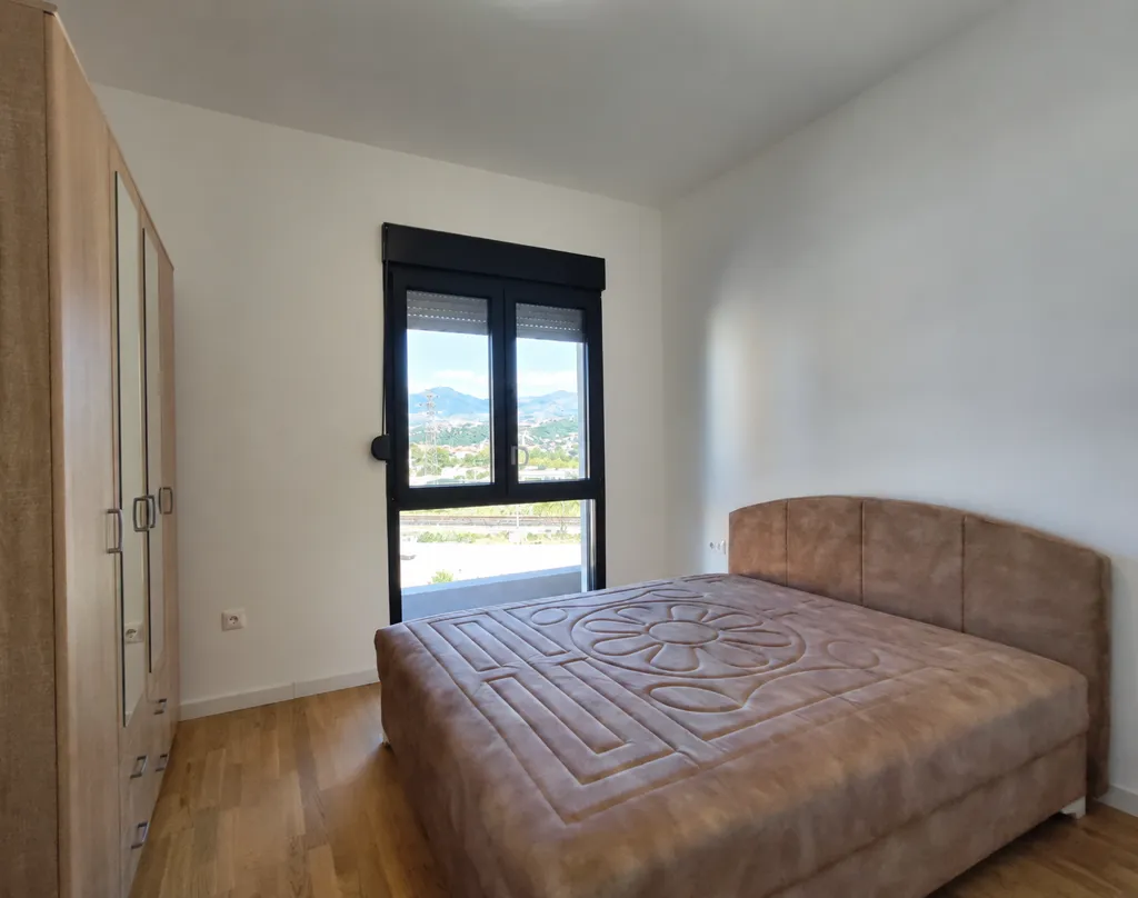 Bright bedroom with a double bed, wardrobe, and a view of nature.