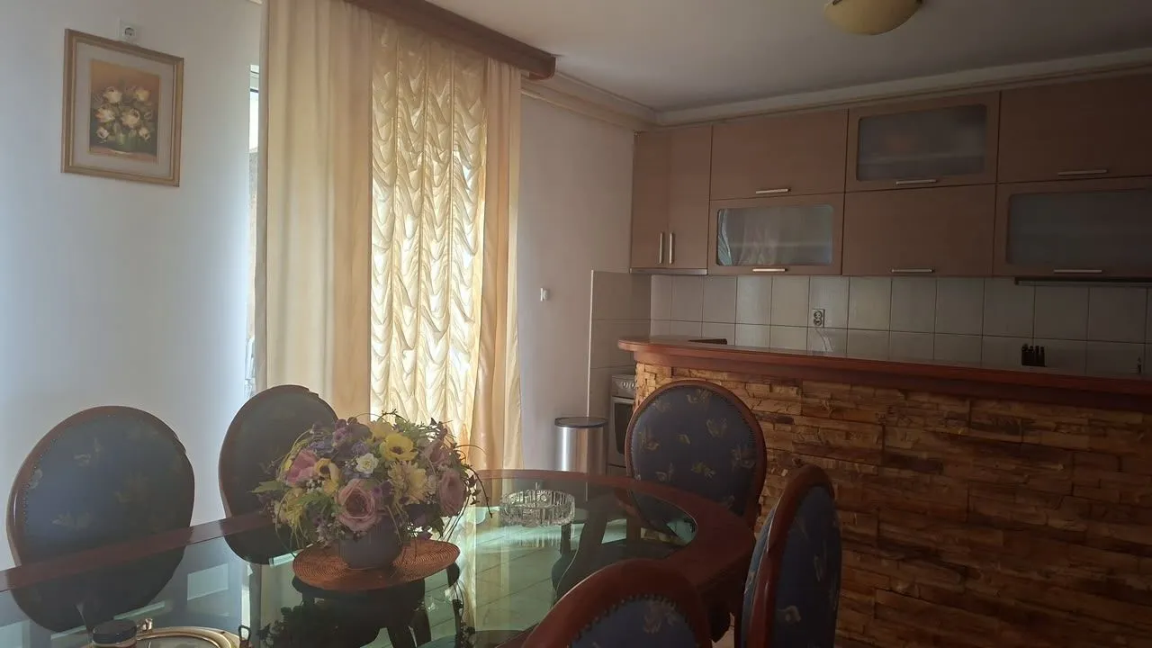 Trpezarija sa stolom i stolicama povezana sa kuhinjom.