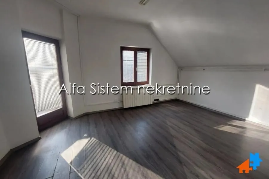 Empty attic room with laminate flooring and windows.