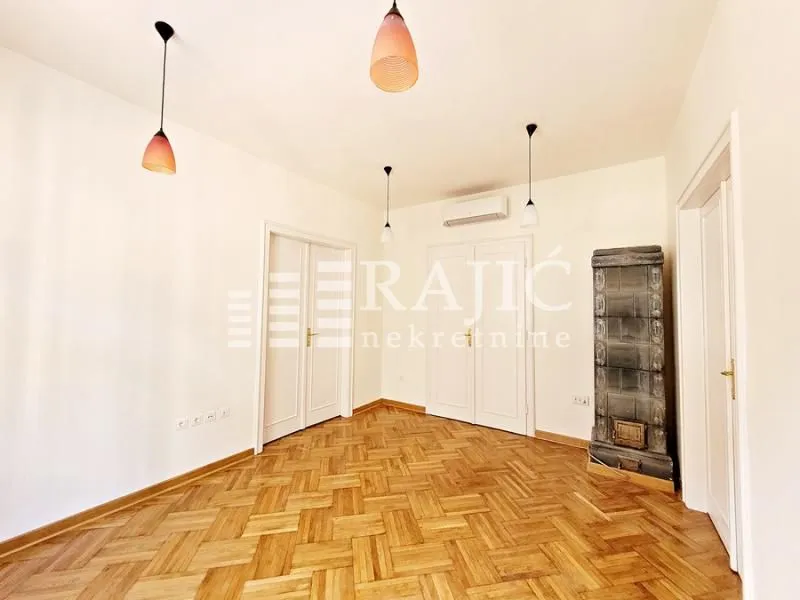 Bright empty room with parquet flooring and a wood stove.