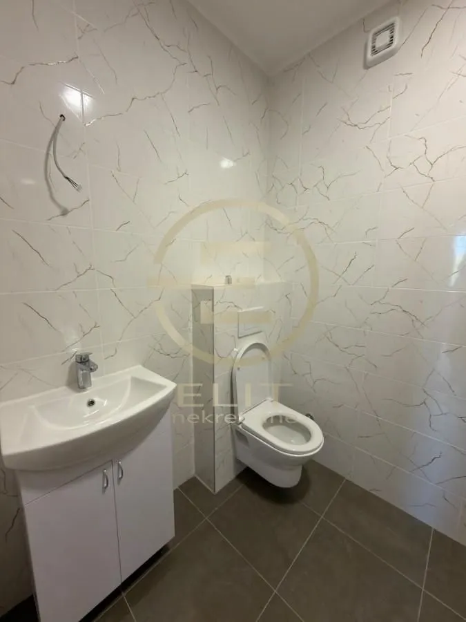Novoopremljeno kupatilo sa umivaonikom i wc šoljom obloženo keramičkim pločicama.