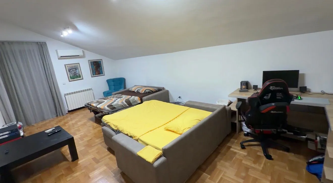 Prostrana spavaća soba sa krevetima, radnim stolom i parketom.