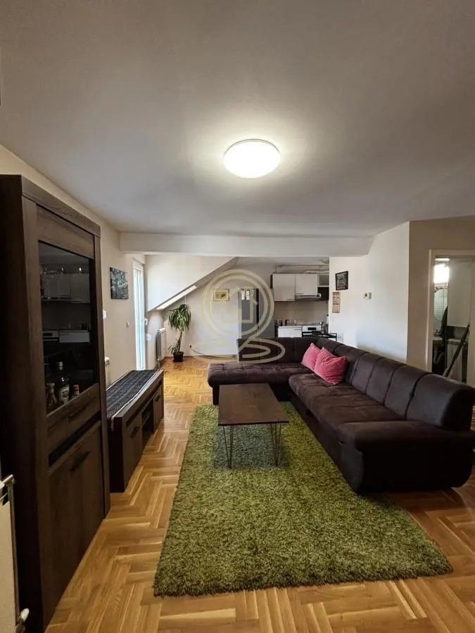 Spacious living room with a sofa and a view of the kitchen.