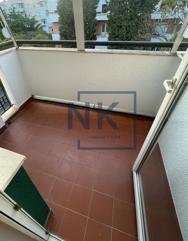 Smaller enclosed balcony with tiled flooring and a view of surrounding buildings.