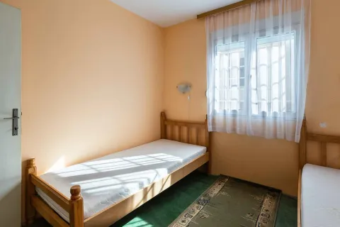 Manja spavaća soba sa dva drvena kreveta i prozorom. - image 31