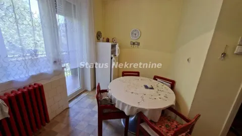Manja trpezarija sa okruglim stolom i crvenim stolicama pored prozora. - image 3