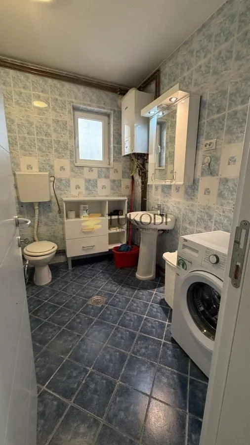 Bathroom equipped with sanitary fixtures, washbasin, cabinet, and washing machine.