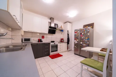 Equipped kitchen with white and dark cabinets and a dining table. - image 10