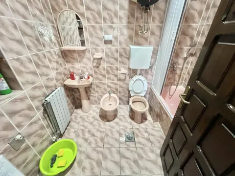 Small tiled bathroom equipped with a bathtub, washbasin, and toilet. - image 9
