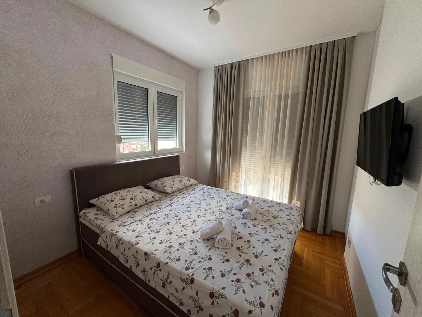 A simple bedroom with a double bed and a wall-mounted TV.