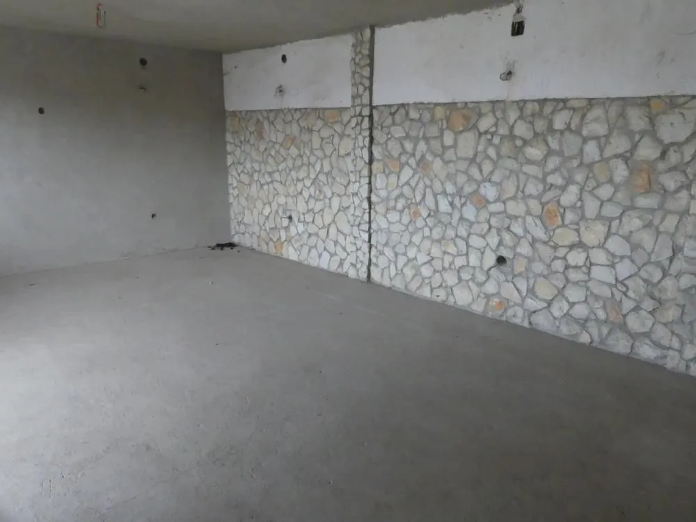 Unfinished room with a stone-clad wall and rough flooring.