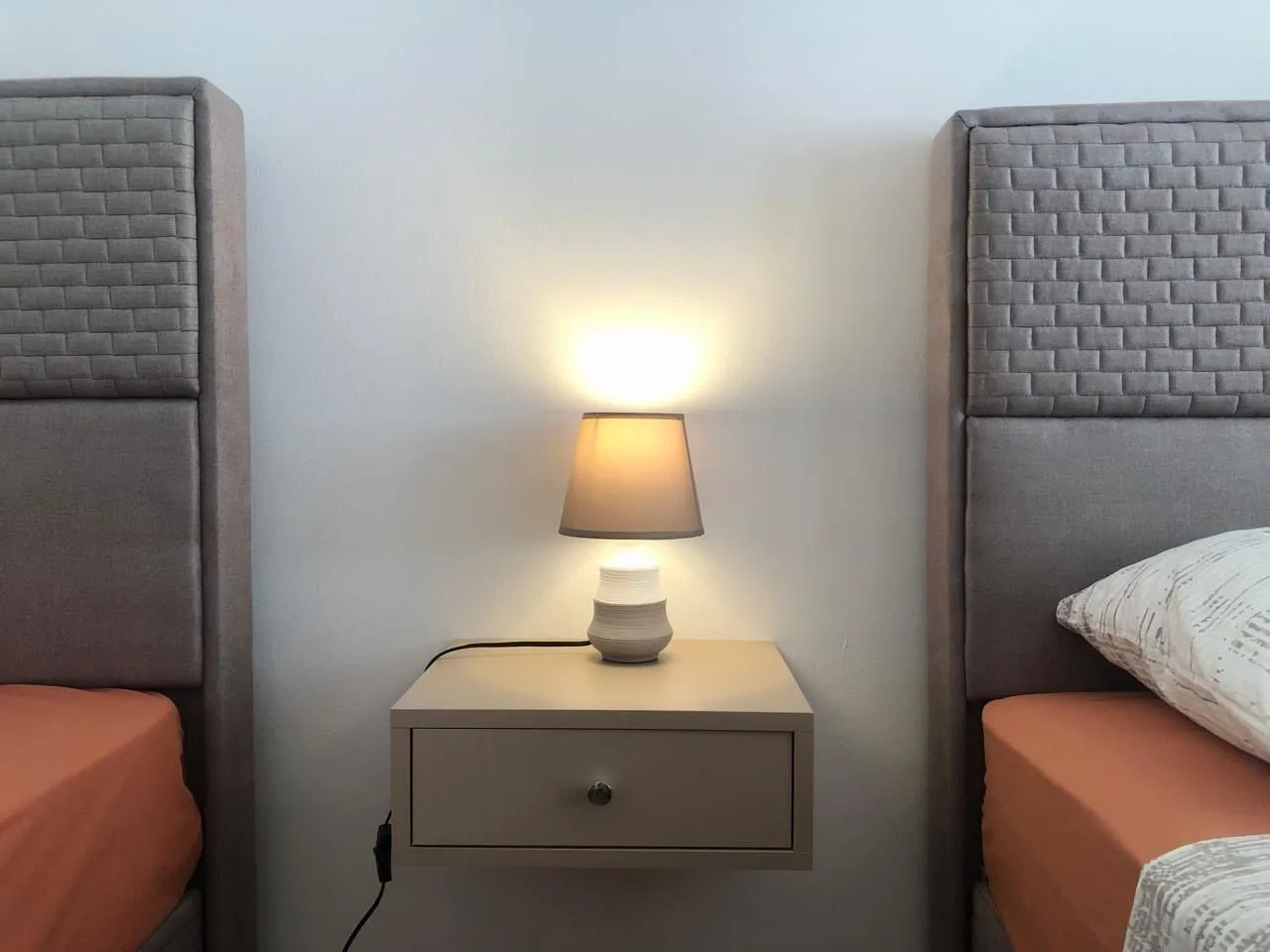 Nightstand with a lamp between two beds in the bedroom.