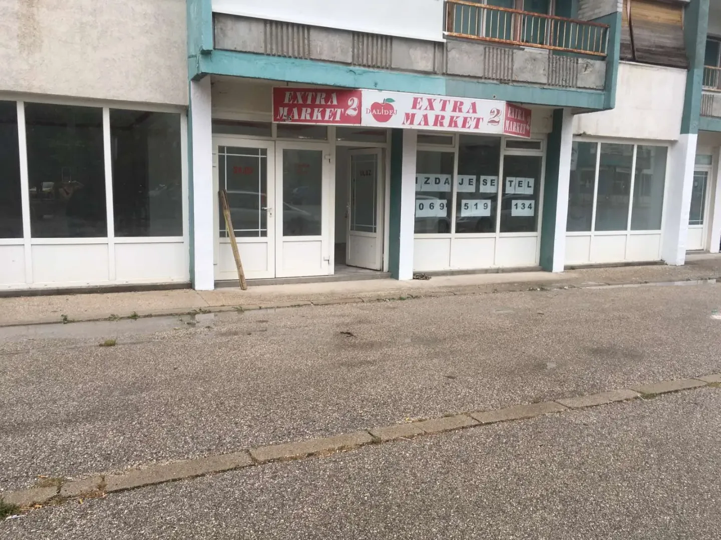 Exterior view of a commercial space with display windows and a market sign.